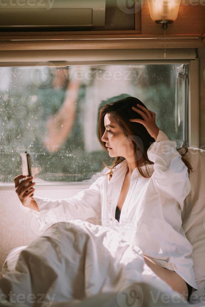 mulher bonita sexy com um smartphone na cama foto