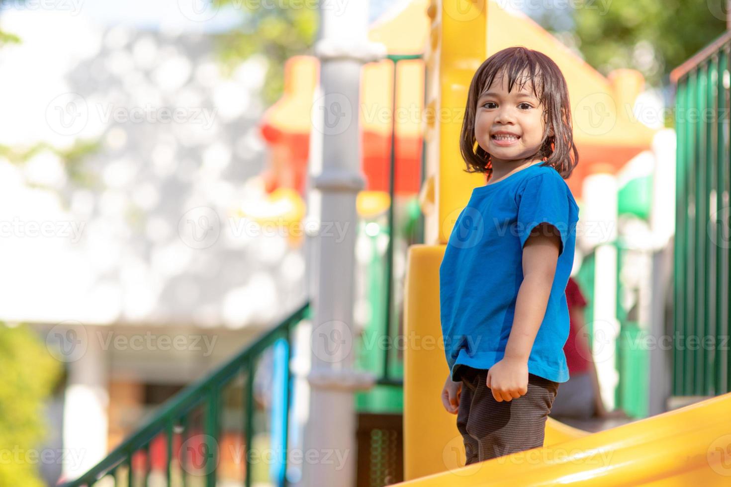 menina bonitinha se divertindo em um playground ao ar livre no verão foto