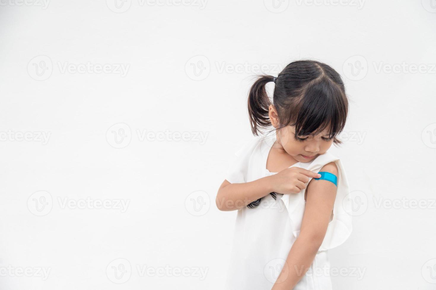 menina asiática mostrando o braço depois de vacinada ou inoculação, imunização infantil, conceito de vacina covid delta foto