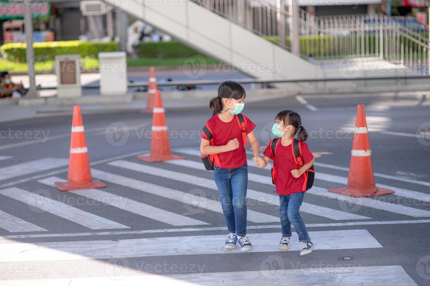 criança em idade escolar usando uma máscara facial durante surto de coronavírus e gripe. irmã voltando para a escola após a quarentena e o bloqueio do covid-19. crianças em máscaras para prevenção de coronavírus. foto