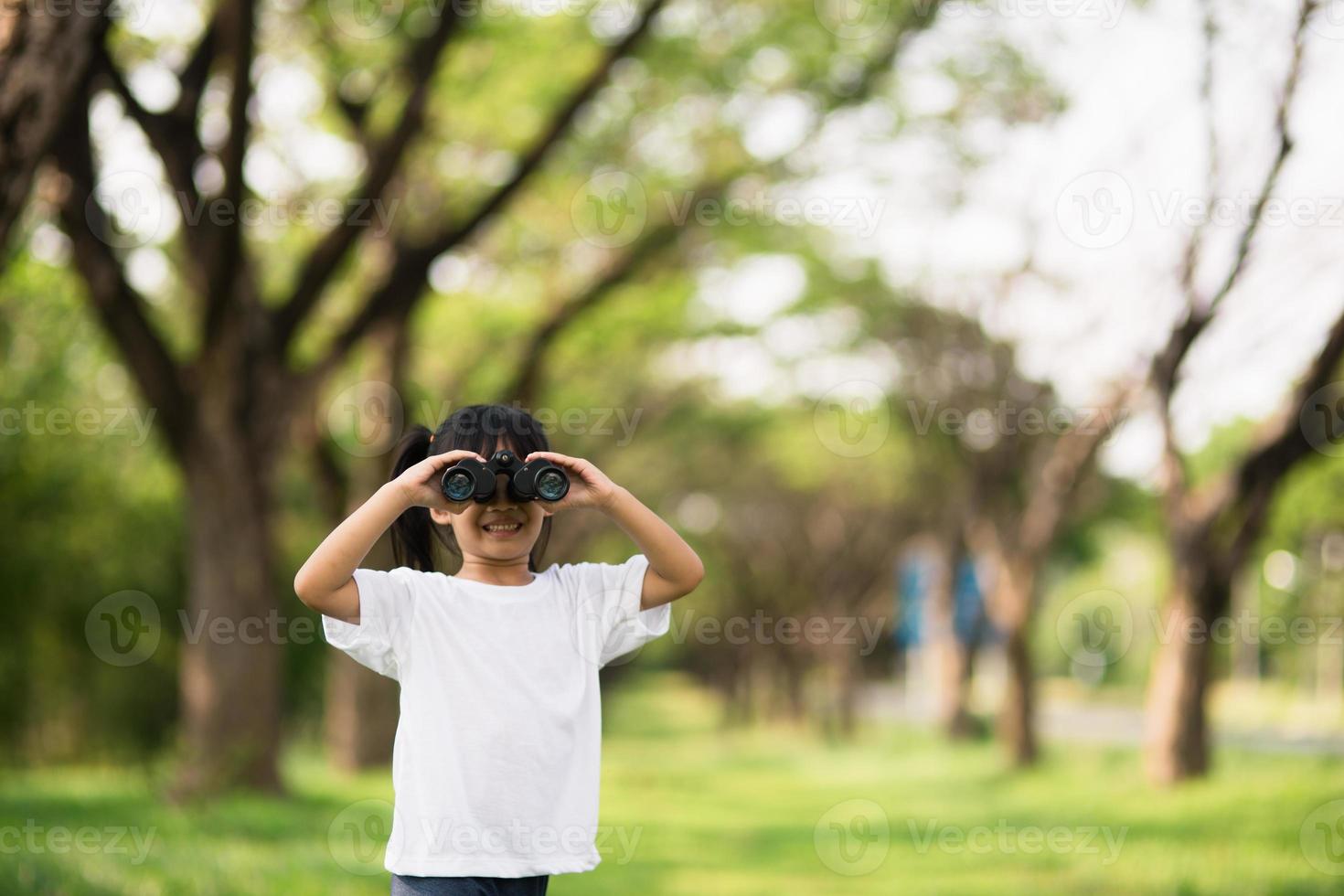 menina criança feliz brincando com binóculos. explorar e conceito de aventura foto