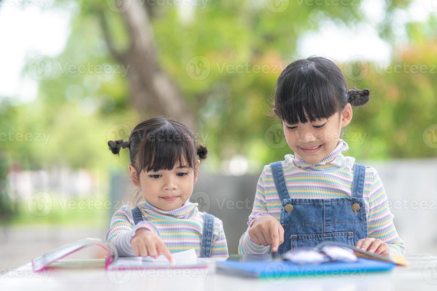 duas estudantes meninas asiáticas lendo o livro na mesa foto