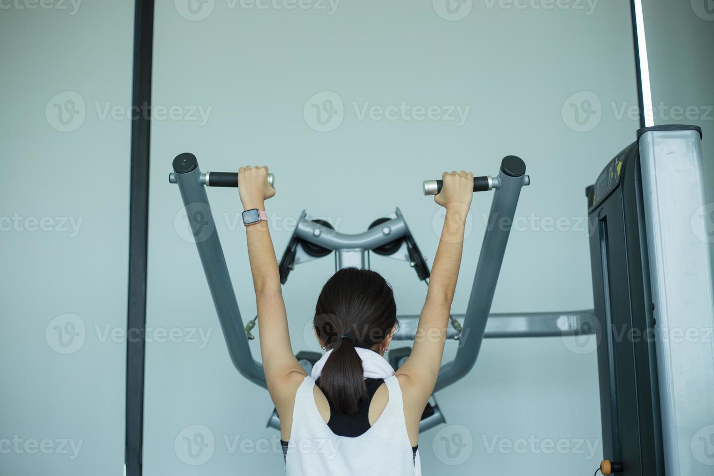 garota jovem fitness executar exercício com máquina de exercícios no ginásio foto