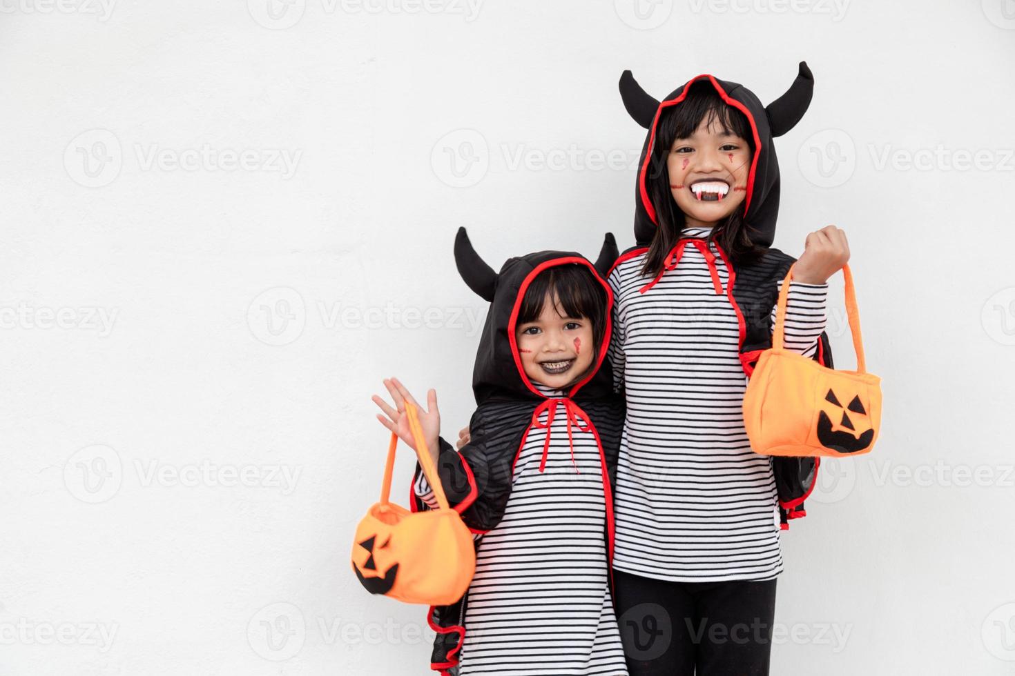 feliz dia das bruxas duas crianças em trajes de halloween e com abóboras em fundo branco foto