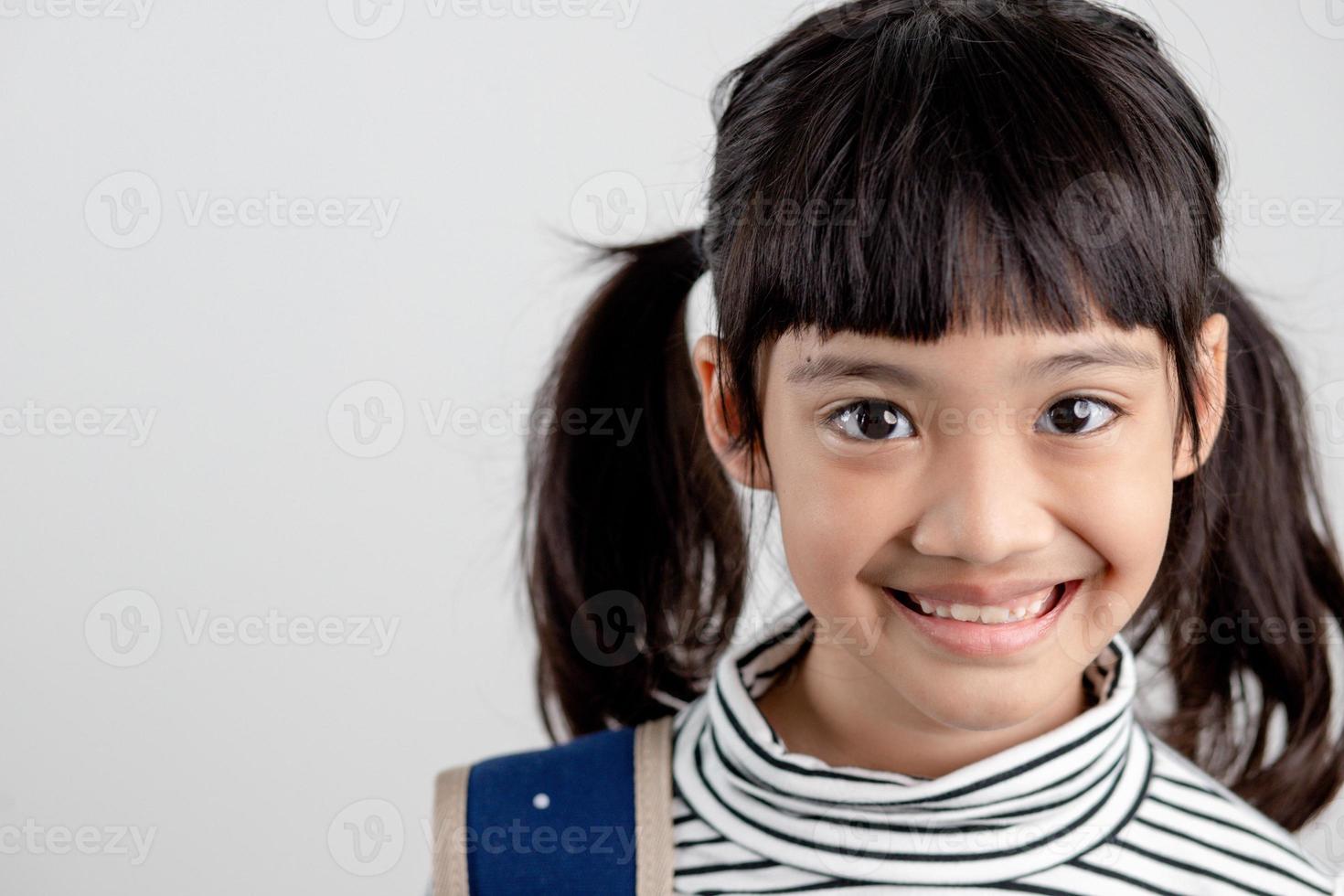 retrato de criança asiática em uniforme escolar com mochila em fundo branco foto