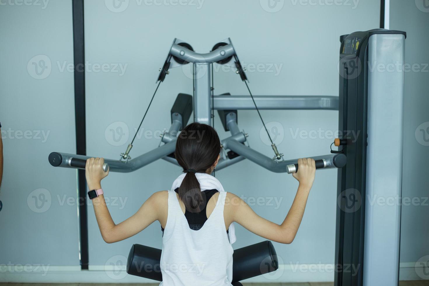 garota jovem fitness executar exercício com máquina de exercícios no ginásio foto