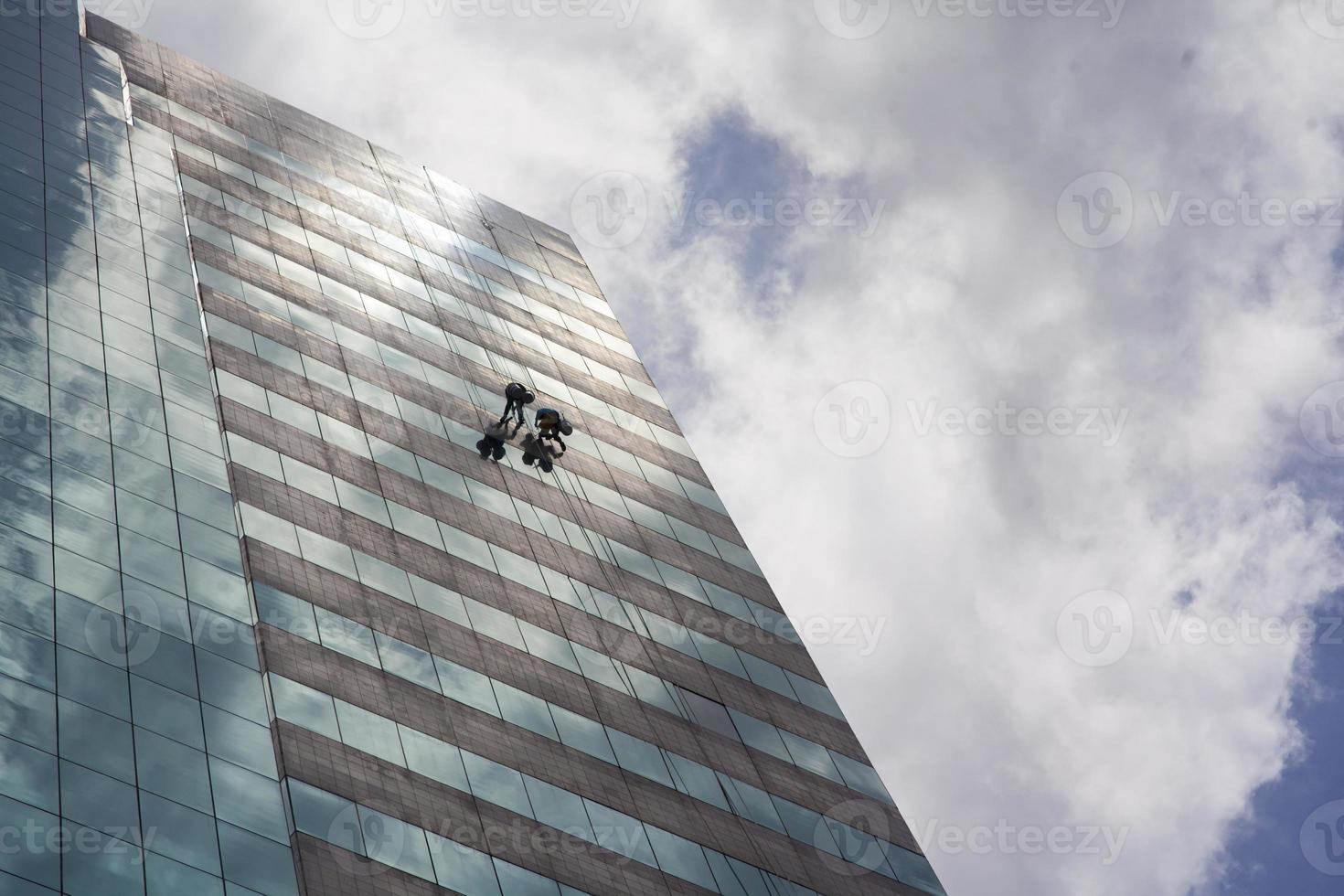 grupo de trabalhadores limpando o serviço de janelas em prédio alto foto