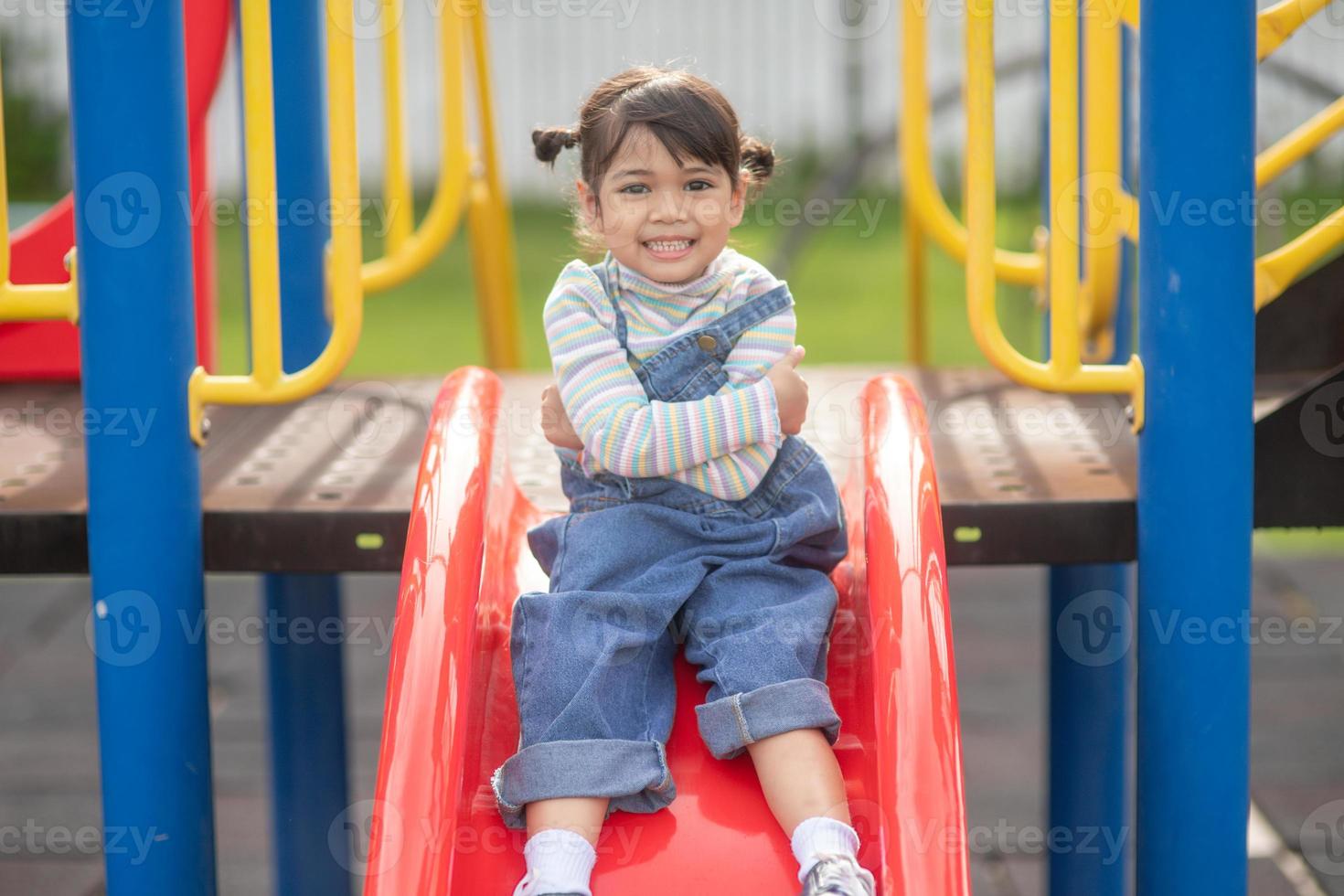 menina criança asiática brincando no playground ao ar livre. as crianças brincam na escola ou no jardim de infância. atividade de verão saudável para crianças. foto