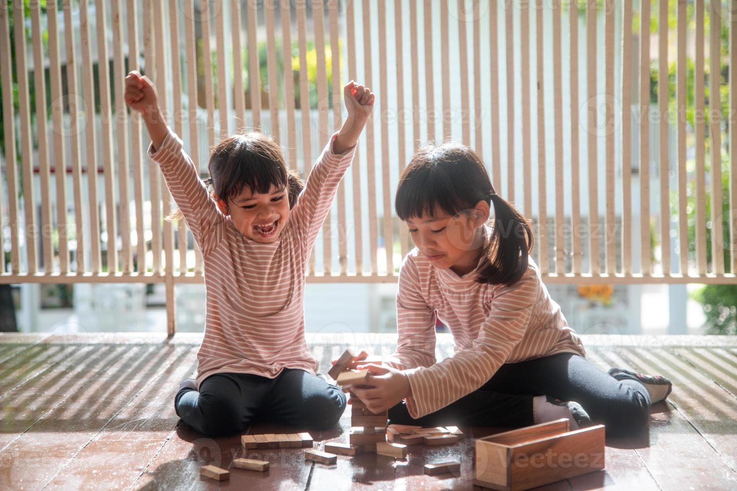 duas garotas asiáticas jogando pilhas de madeira em casa foto