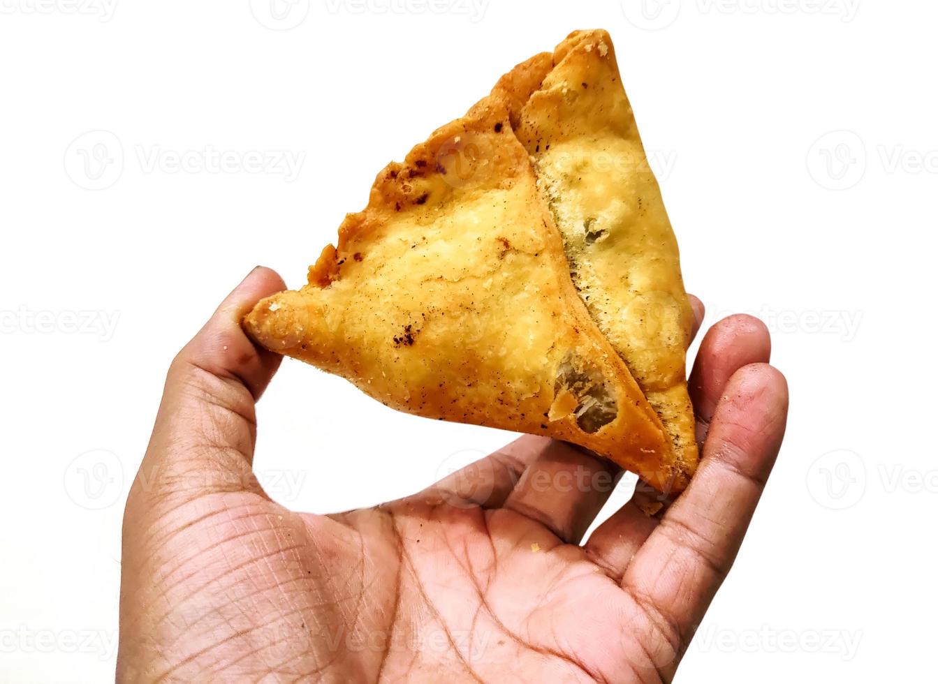 um homem segurando samosa frita na mão foto