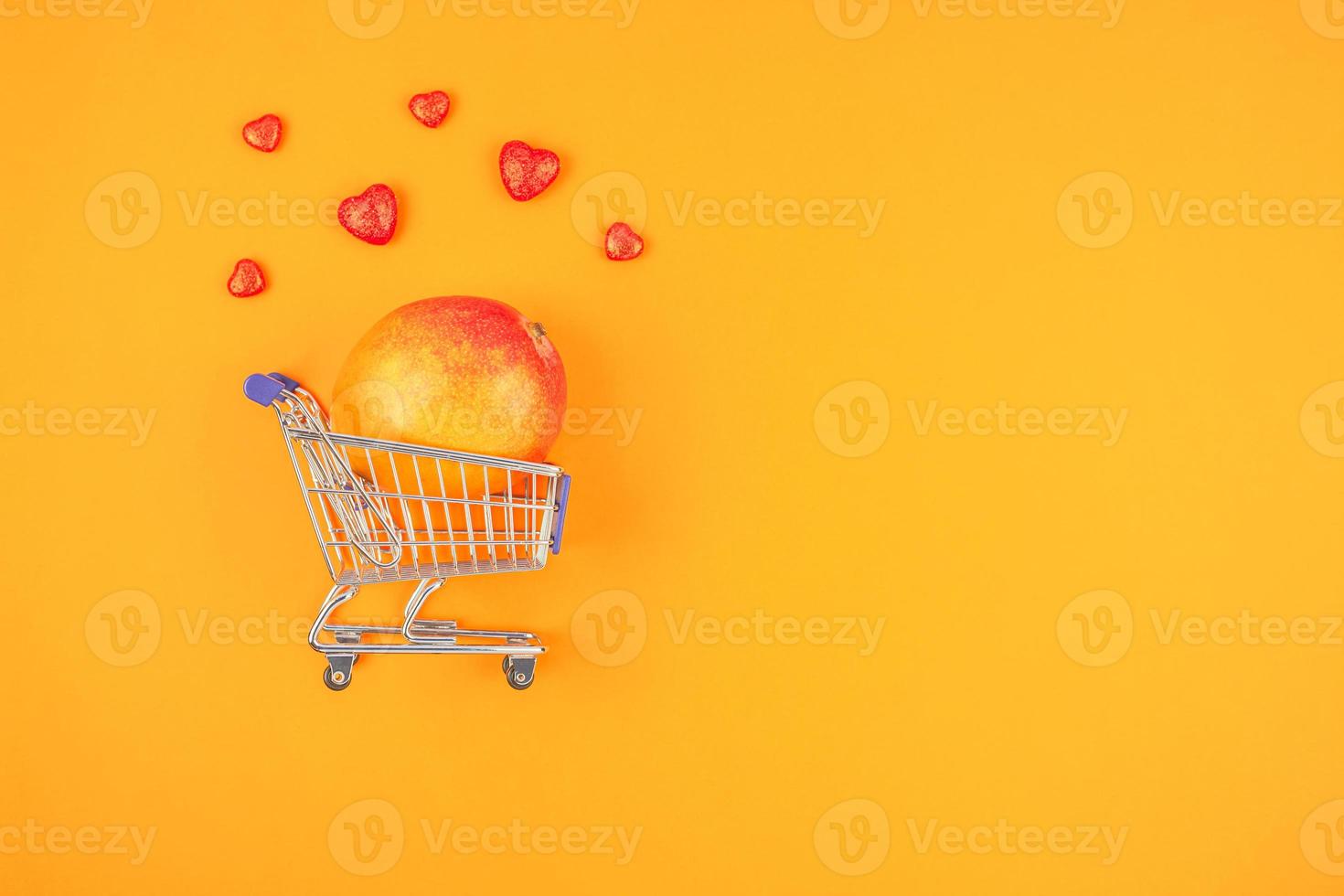 fruta manga no carrinho de compras em fundo laranja foto
