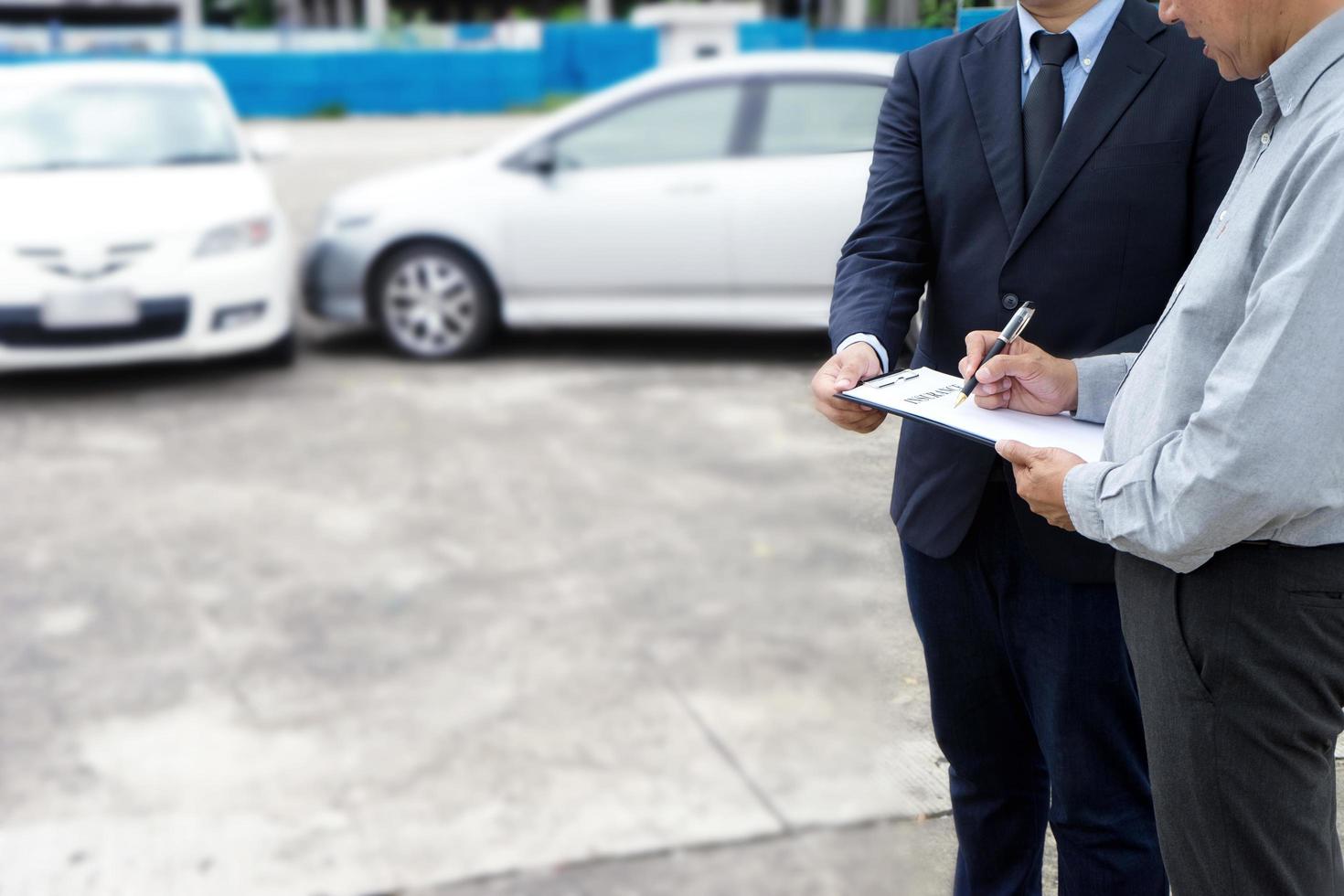 agente de seguros examinando um acidente de carro foto