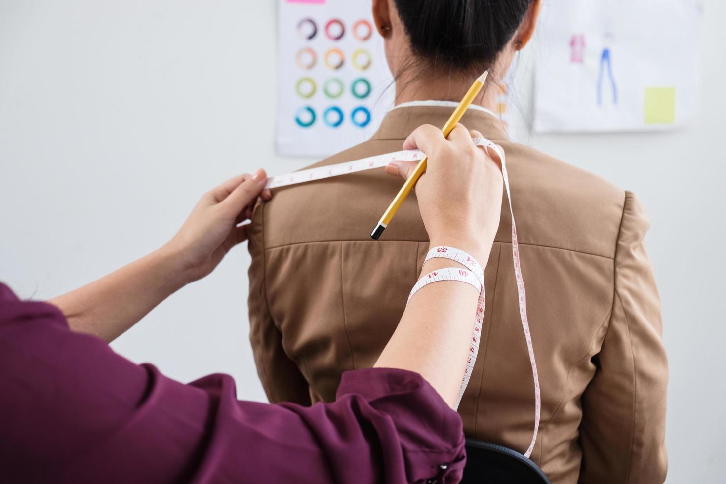 designer jovem medindo roupas para cliente foto