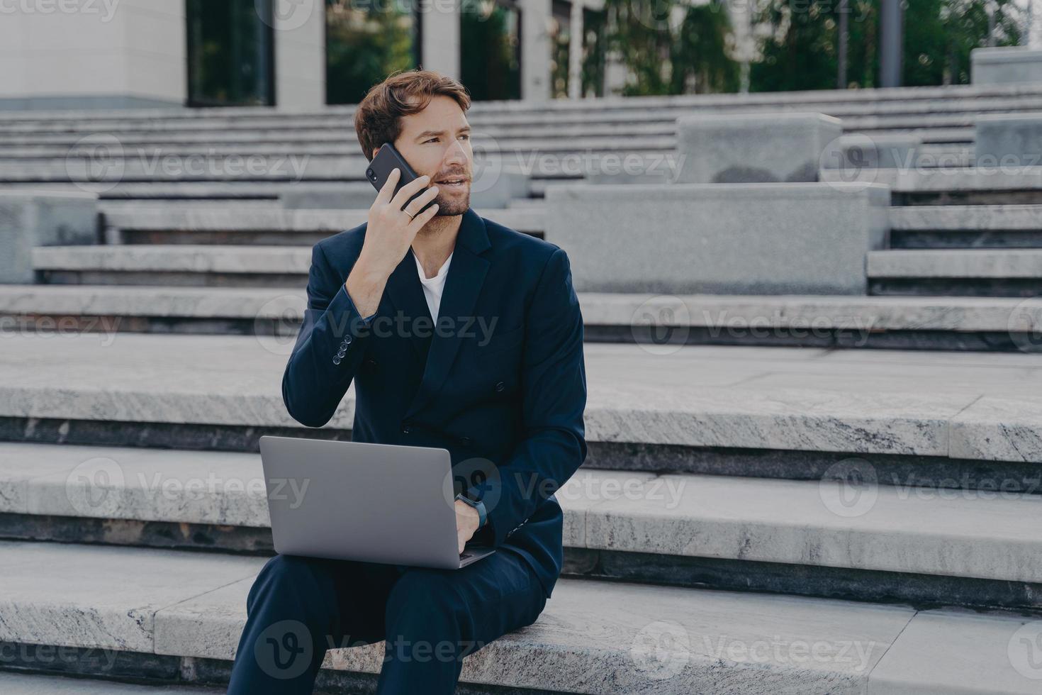 empresário masculino ocupado ocupado trabalhando com dados estatísticos discute o desempenho via telefone celular foto