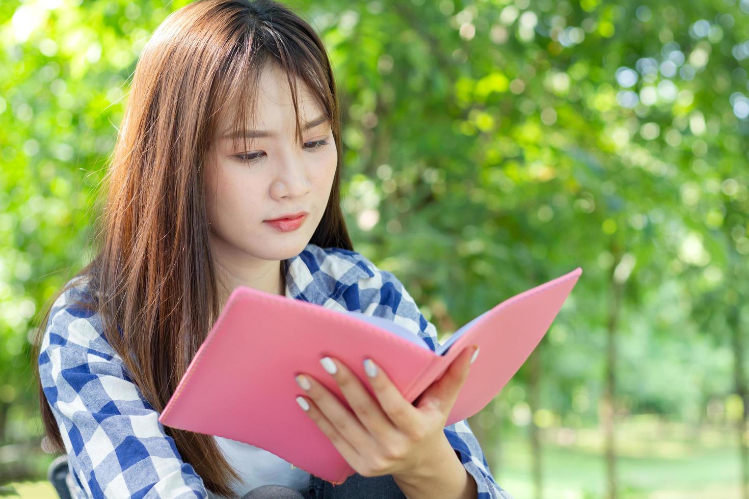 mulher asiática lendo um livro no parque foto