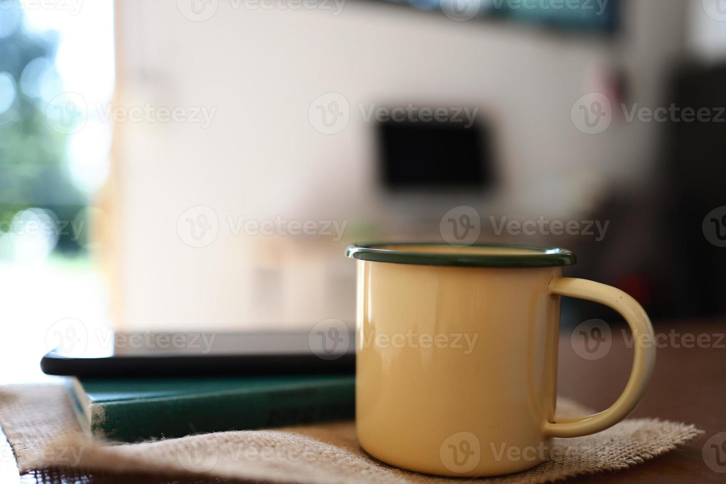 canecas de café amarelas, telefones e livros na mesa de madeira dentro de casa. foto