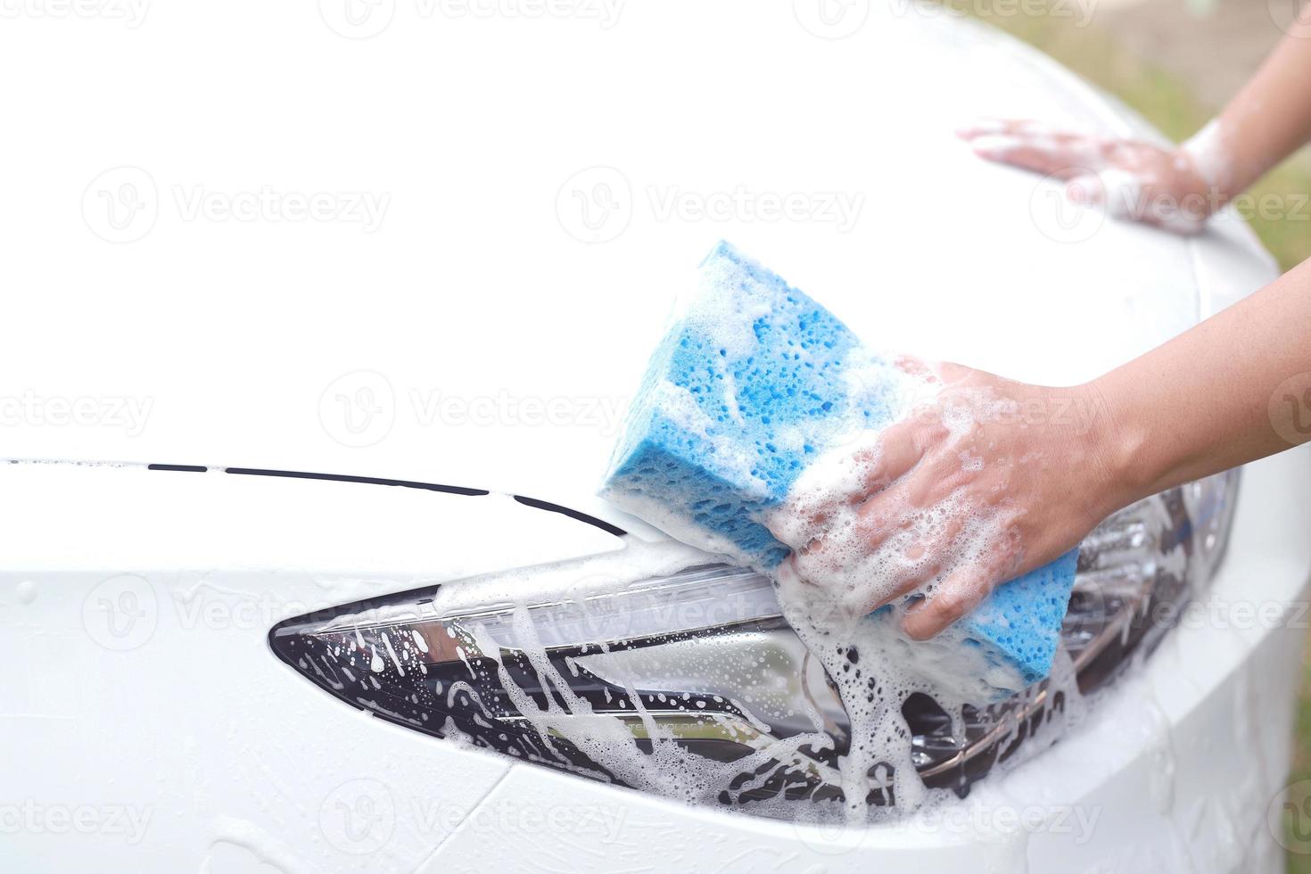 este homem está lavando o carro e limpando o carro. foto