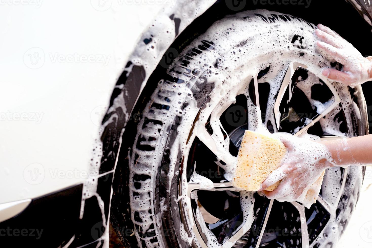 este homem está lavando o carro e limpando o carro. foto