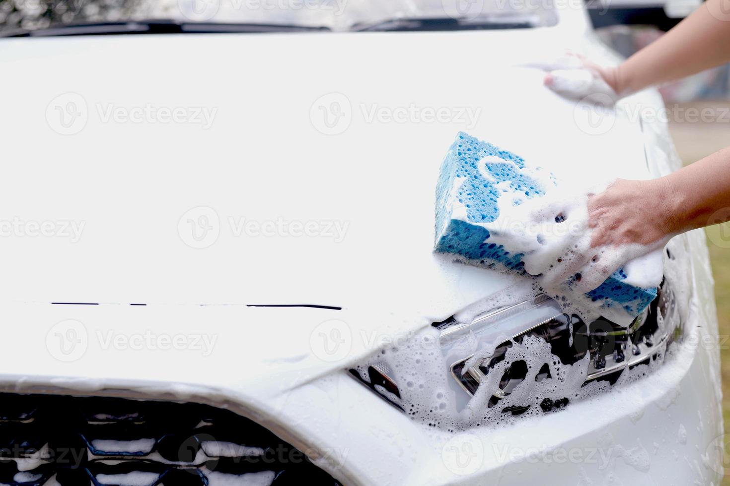 este homem está lavando o carro e limpando o carro. foto