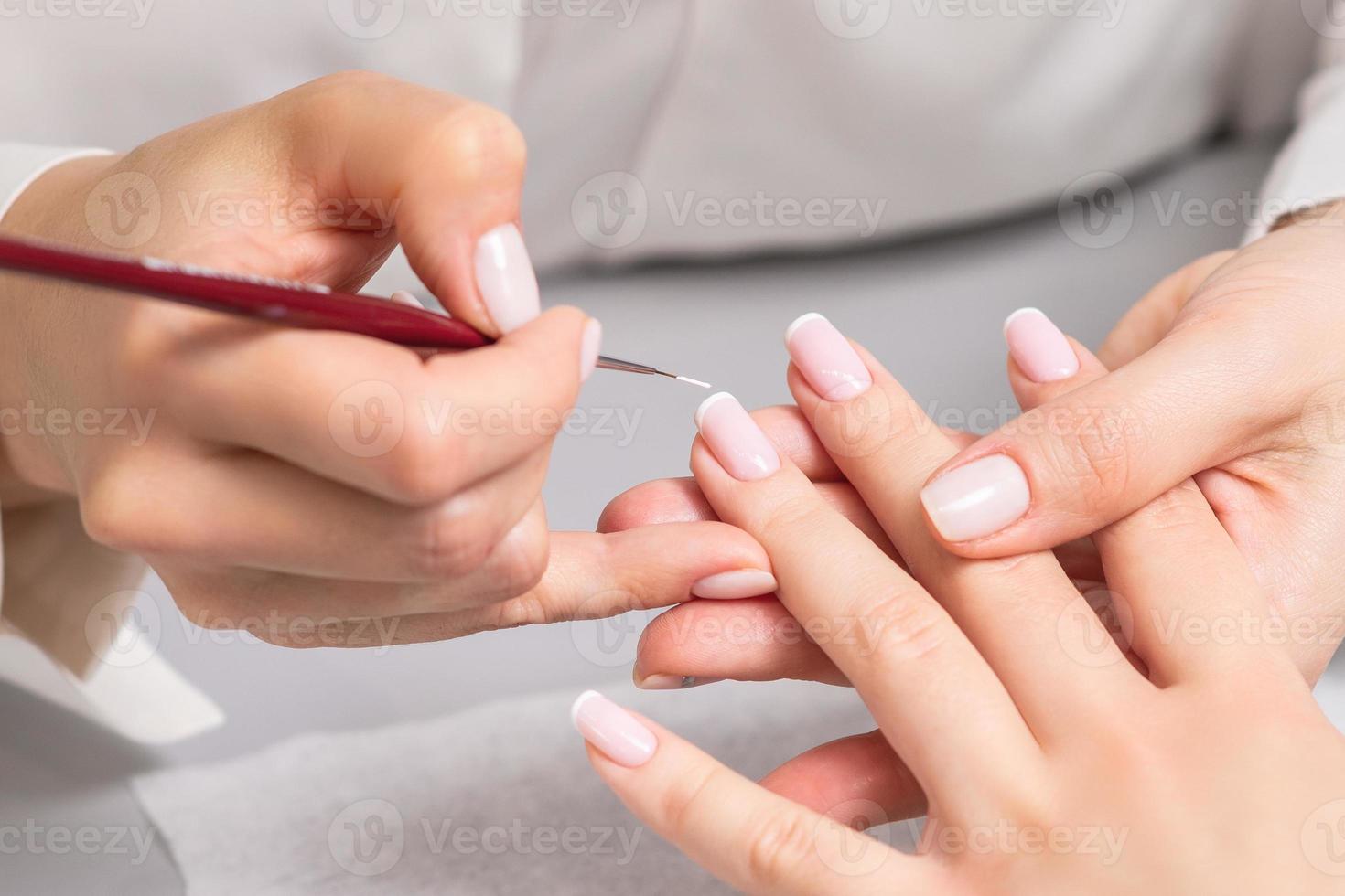 mulher recebendo manicure francesa por esteticista foto