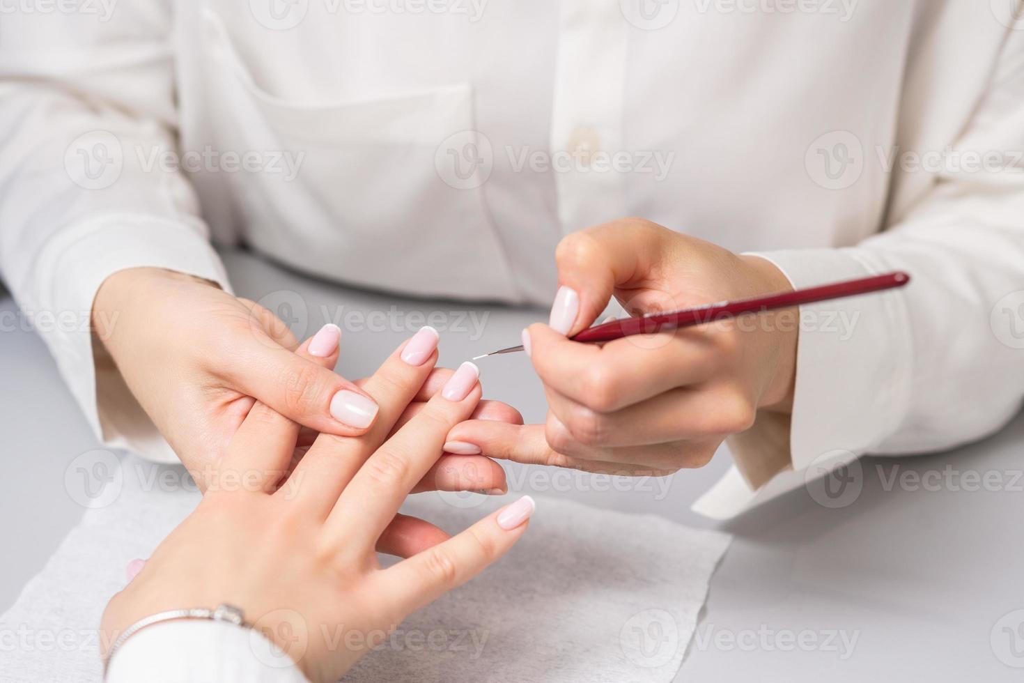 mulher recebendo manicure francesa por esteticista foto