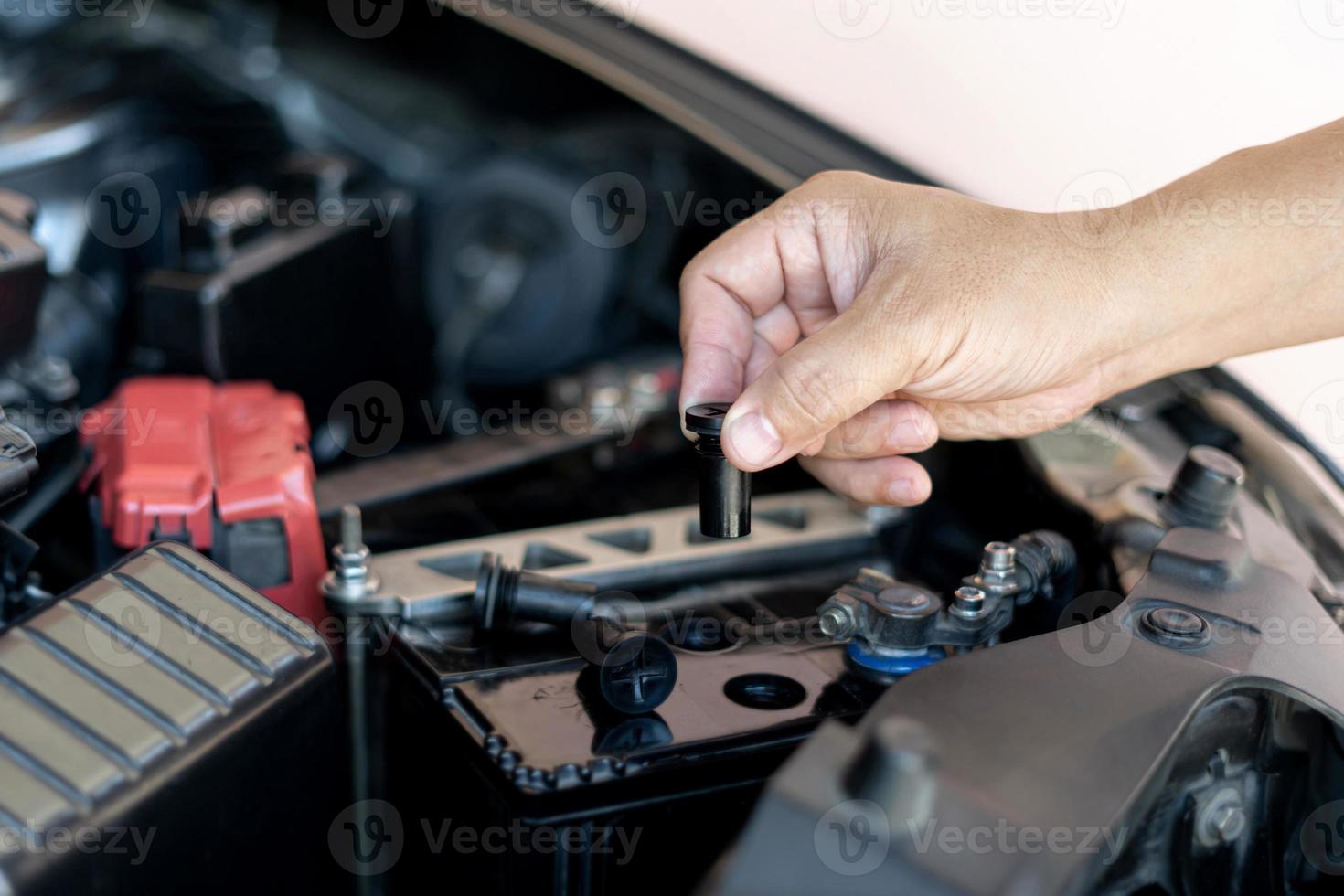 um homem abre a tampa da bateria para adicionar manutenção e inspeções destiladas para prolongar a vida útil da bateria do carro foto