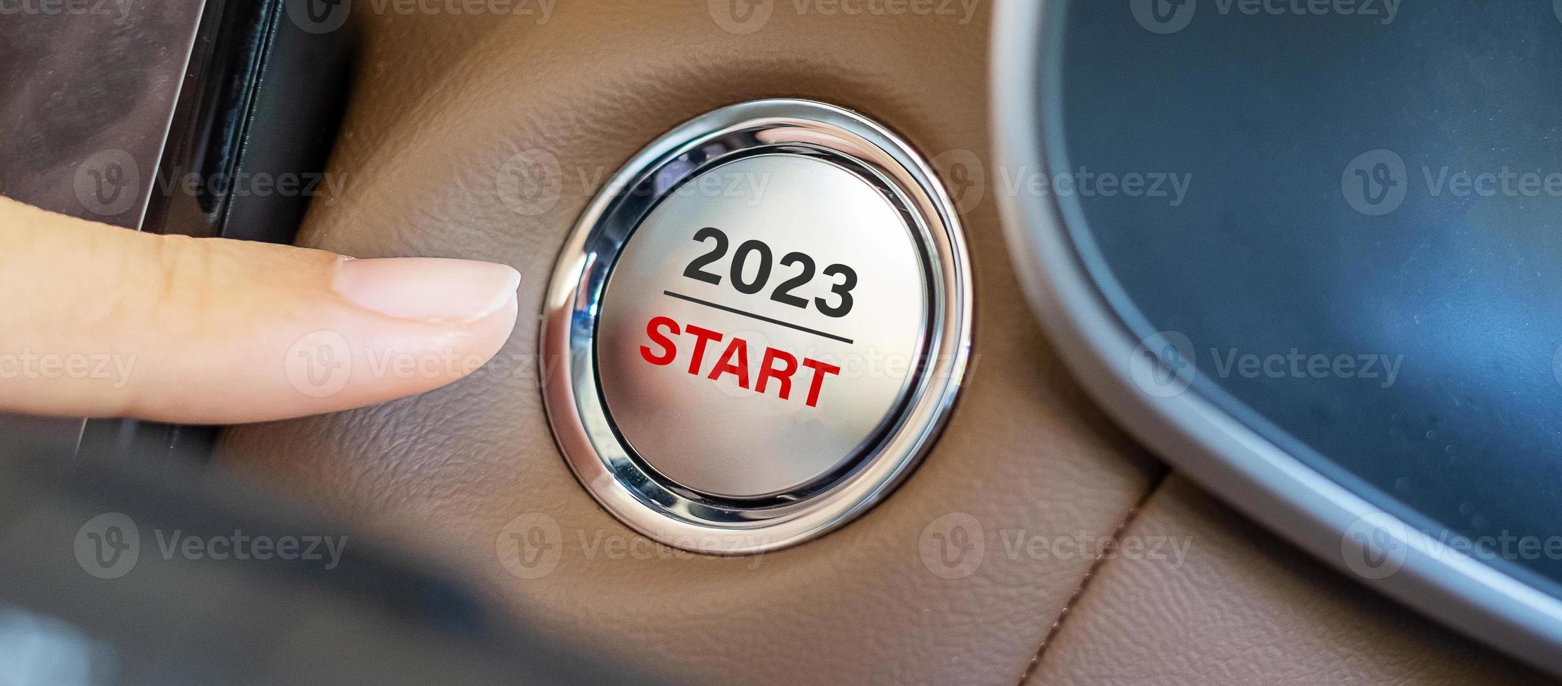 dedo pressione um botão de ignição do carro com o texto inicial de 2023 dentro do automóvel. ano novo novo você, previsão, resolução, motivação, mudança, objetivo, visão, inovação e conceito de planejamento foto