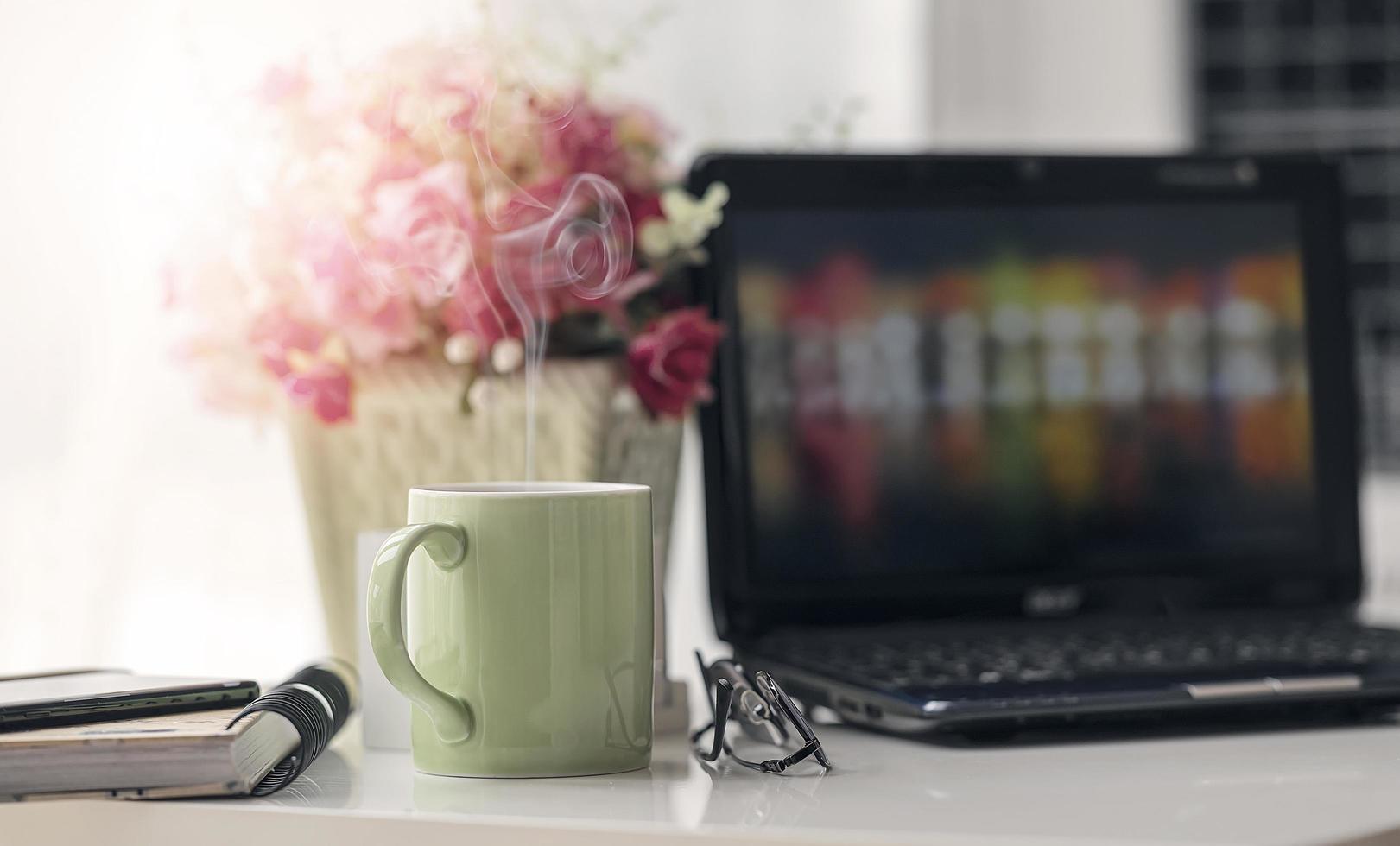 vapor saindo de uma caneca verde em um escritório doméstico foto