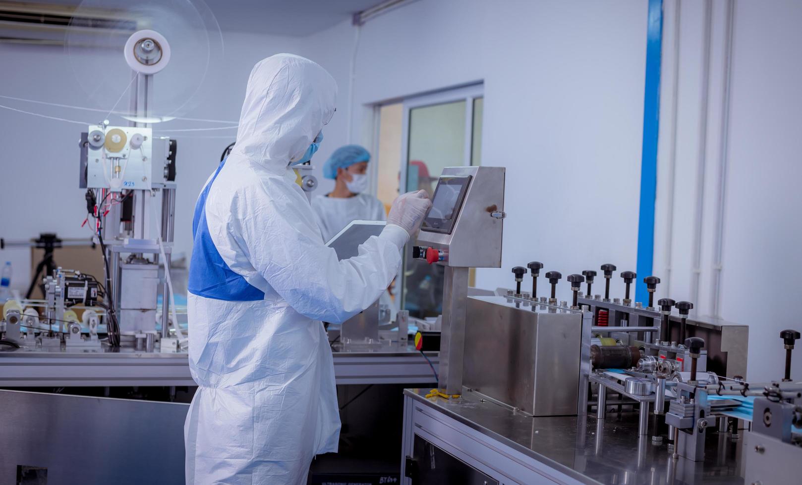 trabalhador técnico usando conjunto de proteção, luva são inspecionados com verificação do processo de fabricação da máscara facial para segurança e proteção contra vírus. foto