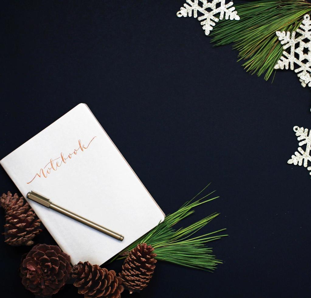 caderno e caneta com pinhas e flocos de neve foto