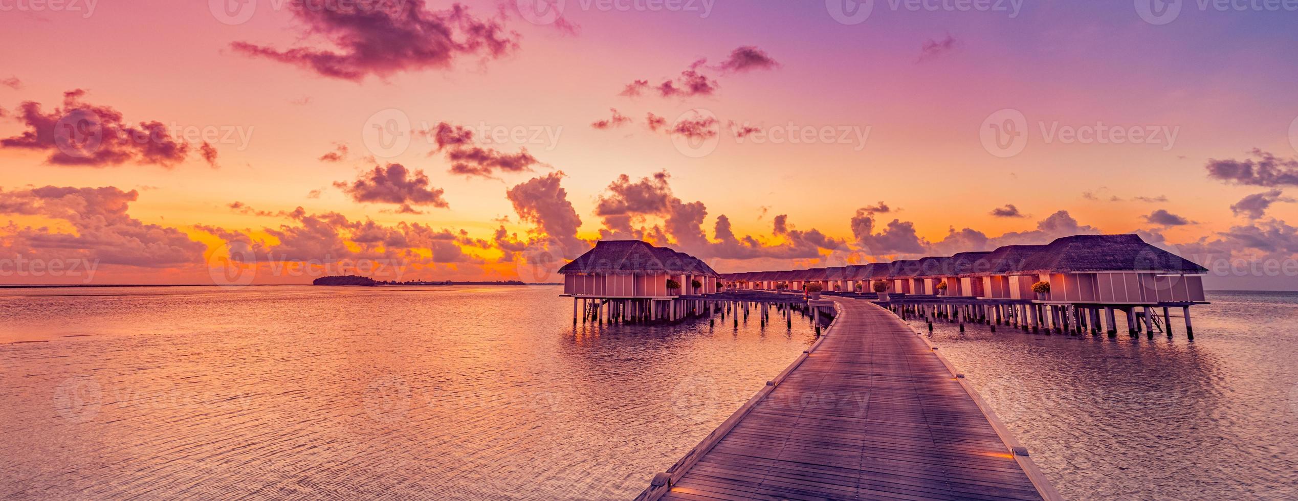 incrível panorama do pôr do sol tropical nas ilhas maldivas. Seascape de villas de resort de luxo com luzes led suaves, céu de sonho colorido. conceito fantástico de férias de verão, paisagem de férias nascer do sol horizonte do mar foto