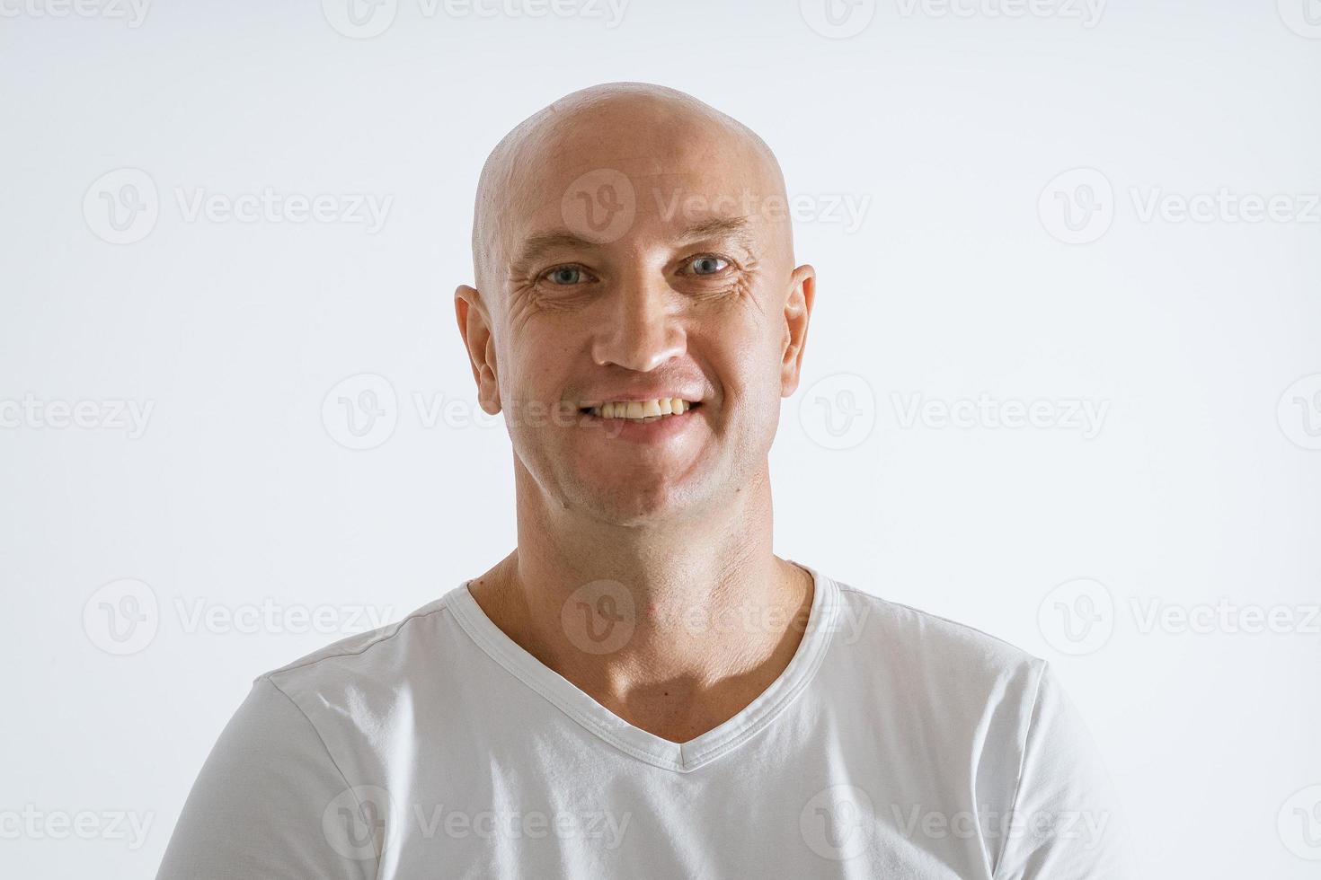 retrato de um homem emocional careca em um fundo branco em uma camiseta branca foto