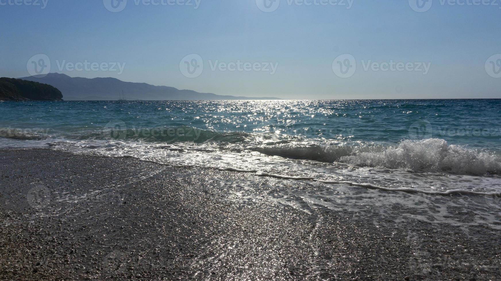 beira-mar à luz do sol. ondas quebram na costa. paisagem de praia de mar ensolarado foto