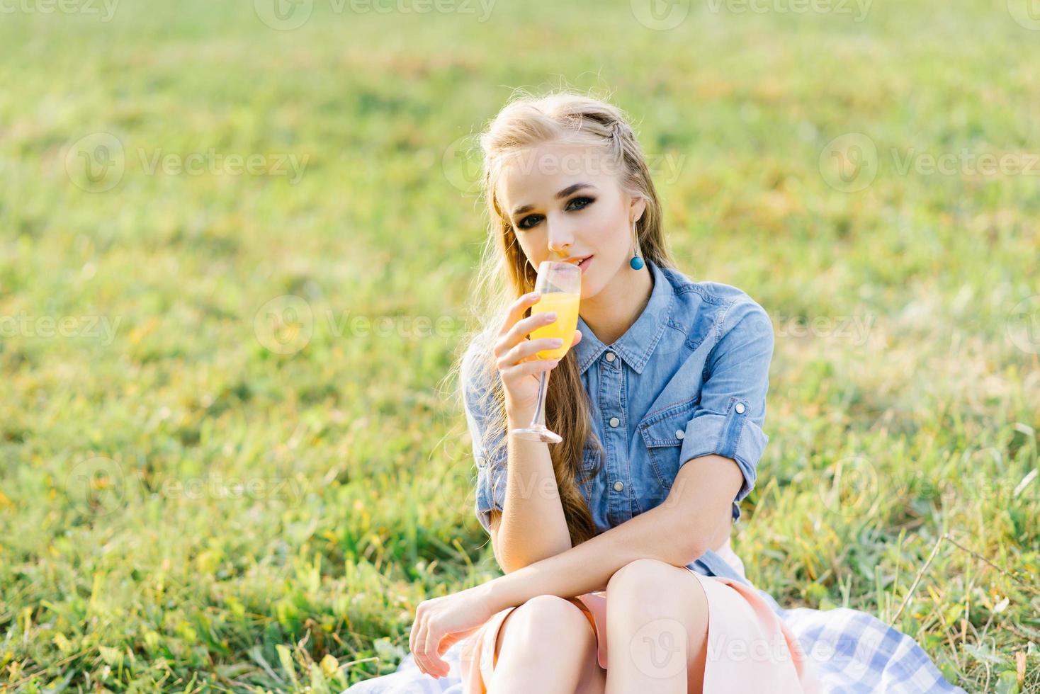 retrato de uma jovem bebendo suco de laranja em um copo em um piquenique de verão no parque ao ar livre foto