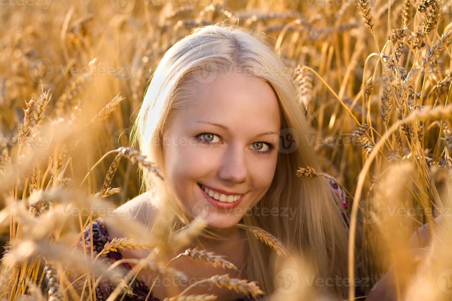 bela mulher loira sorrindo para o campo de trigo closeup foto