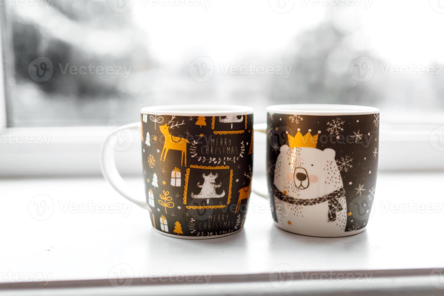 duas xícaras com uma bebida quente, decoração de natal, iluminações em uma janela com fundo de inverno, conceito de férias de inverno em família foto