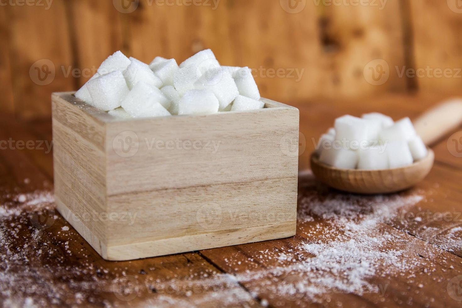 cubos de açúcar em uma tigela com o açúcar derramado foto