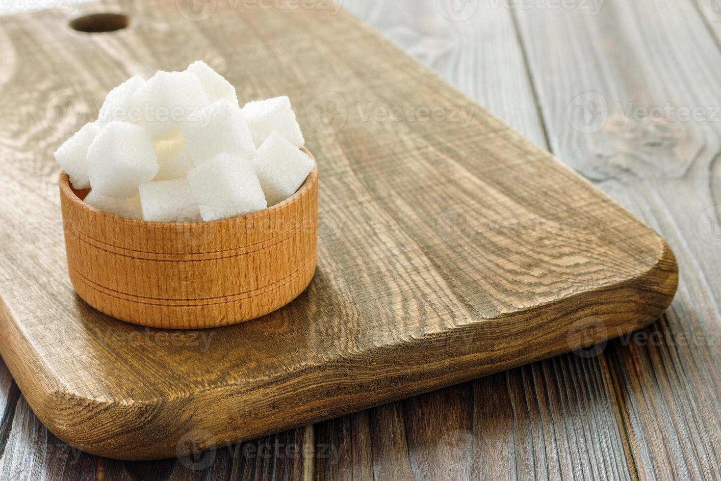 cubos de açúcar na tigela na mesa de madeira. cubos de açúcar branco na tigela foto