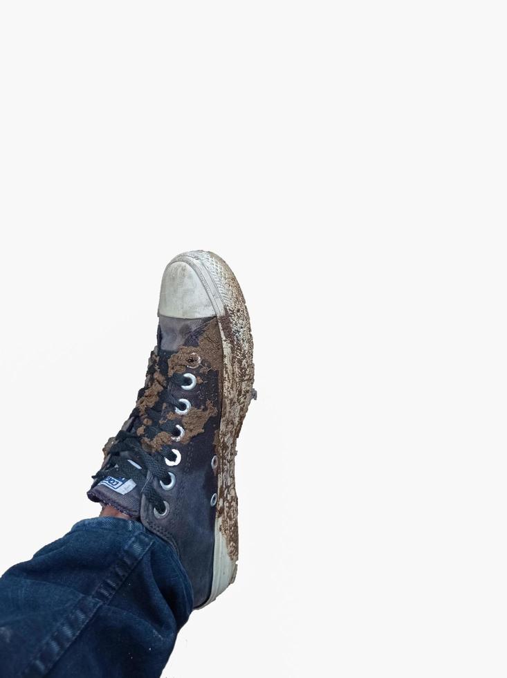 os pés de um homem usando sapatos sujos de lama foto