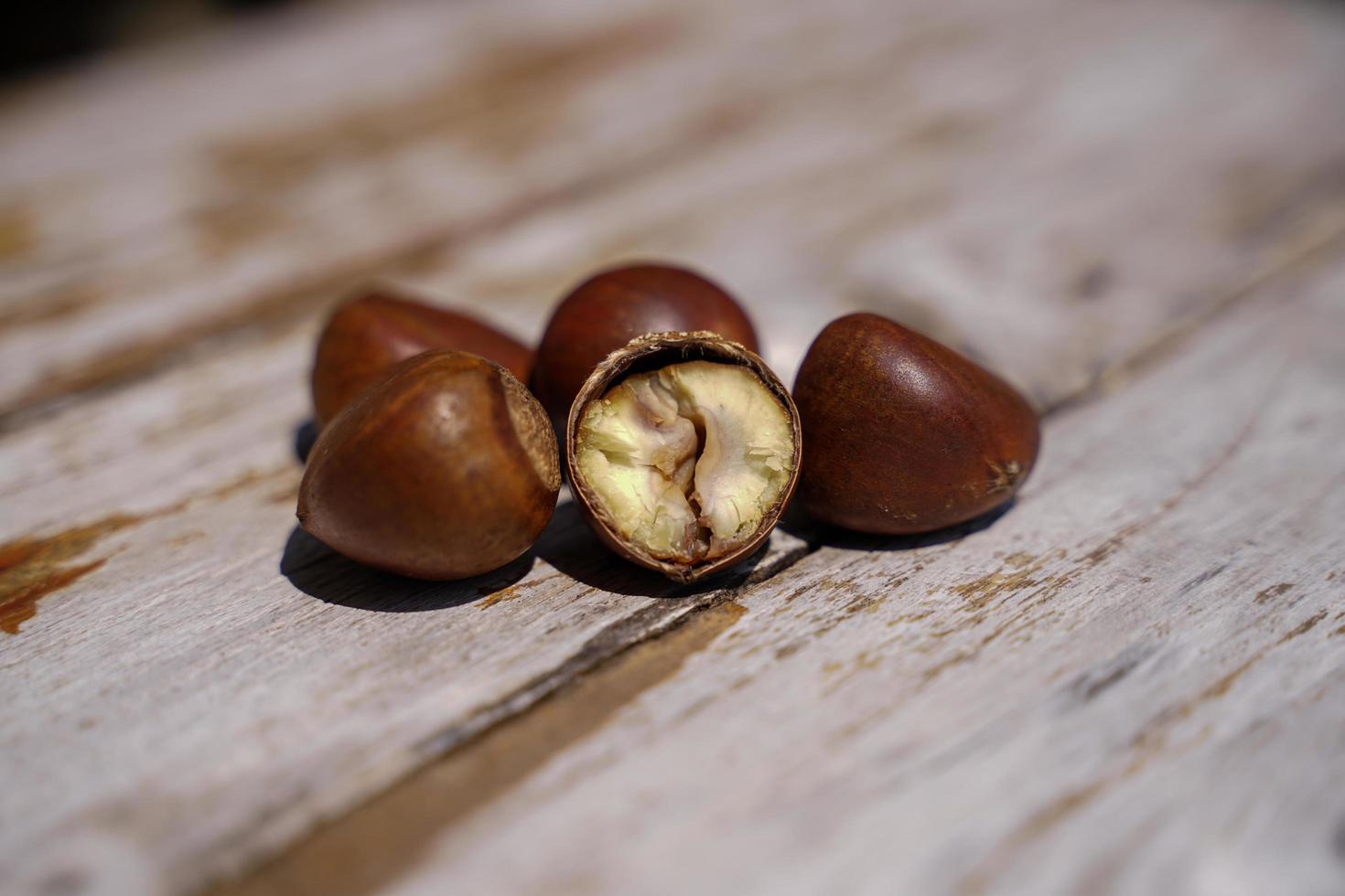 castanhas frescas isoladas em um piso de madeira, as castanhas têm um sabor doce oleoso. foto