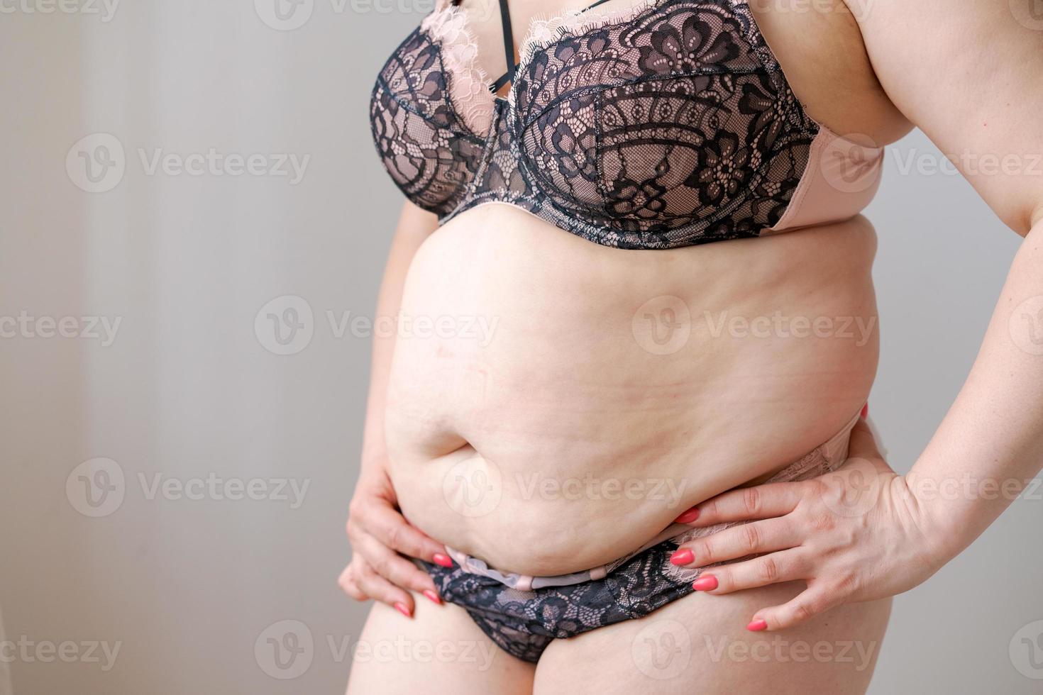 mulher branca de tiro recortado em lingerie segurando a barriga gorda. mulher de grande porte foto