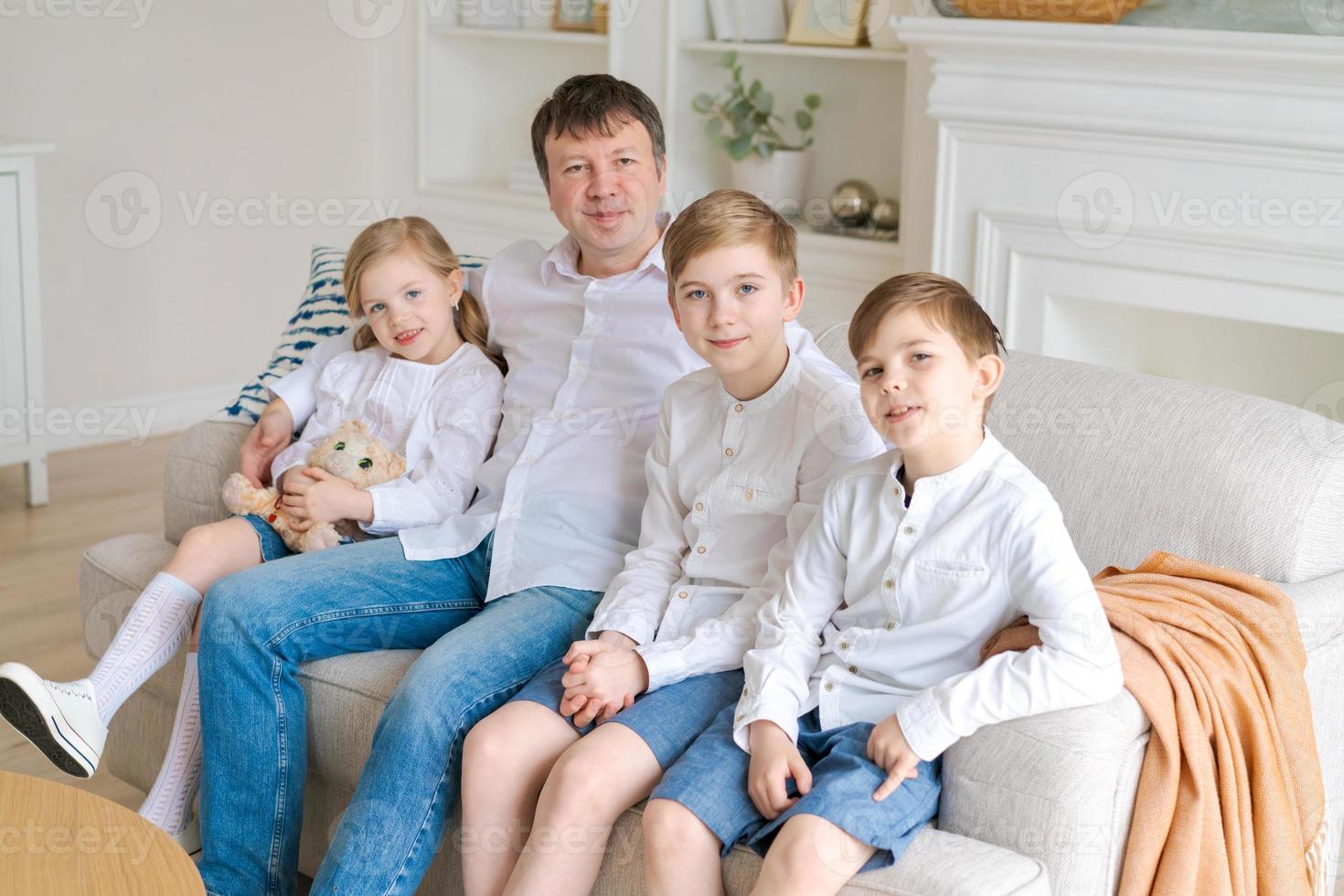 retrato pai de família feliz com crianças pequenas sente-se relaxe no sofá abraçando foto