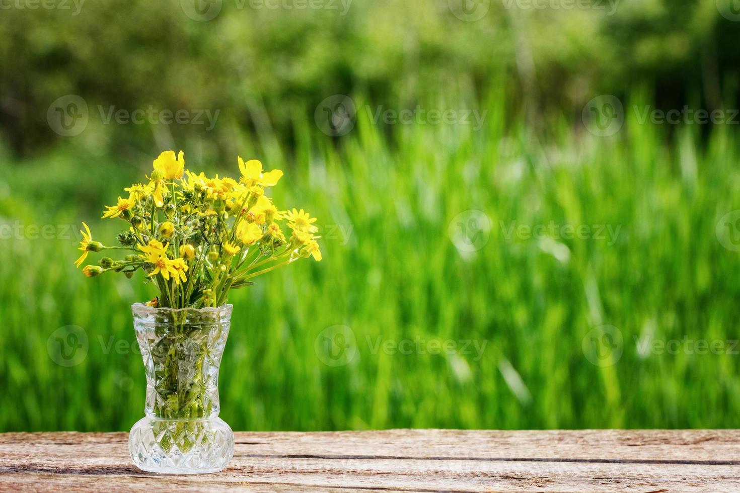 vaso com flores amarelas em cima da mesa em um fundo verde foto