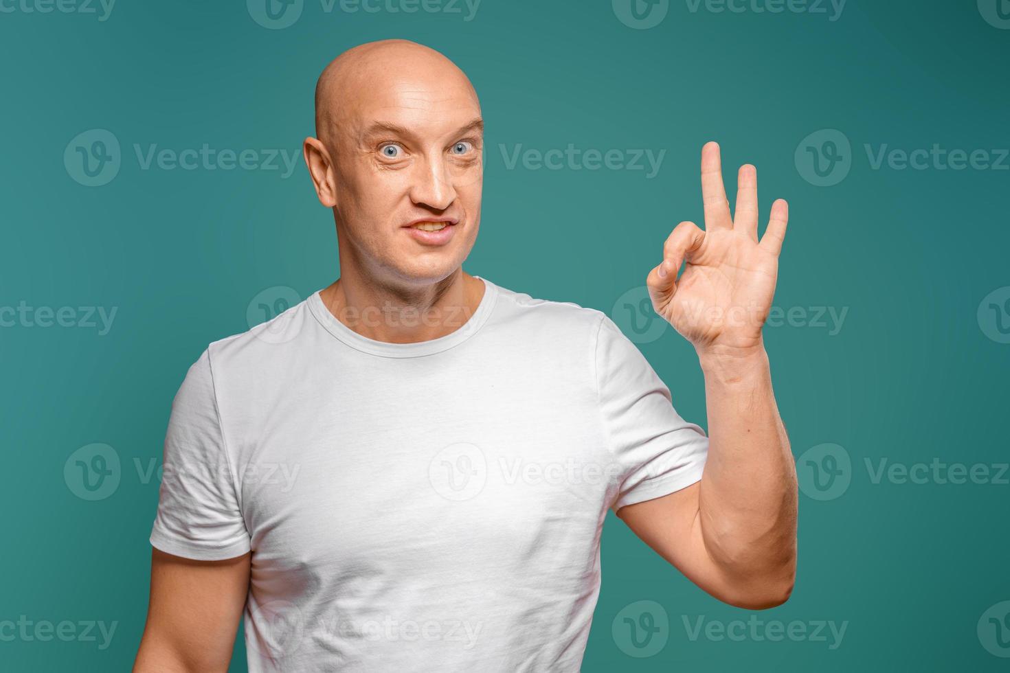 retrato de um homem careca emocional em uma camiseta branca sobre um fundo azul. foto