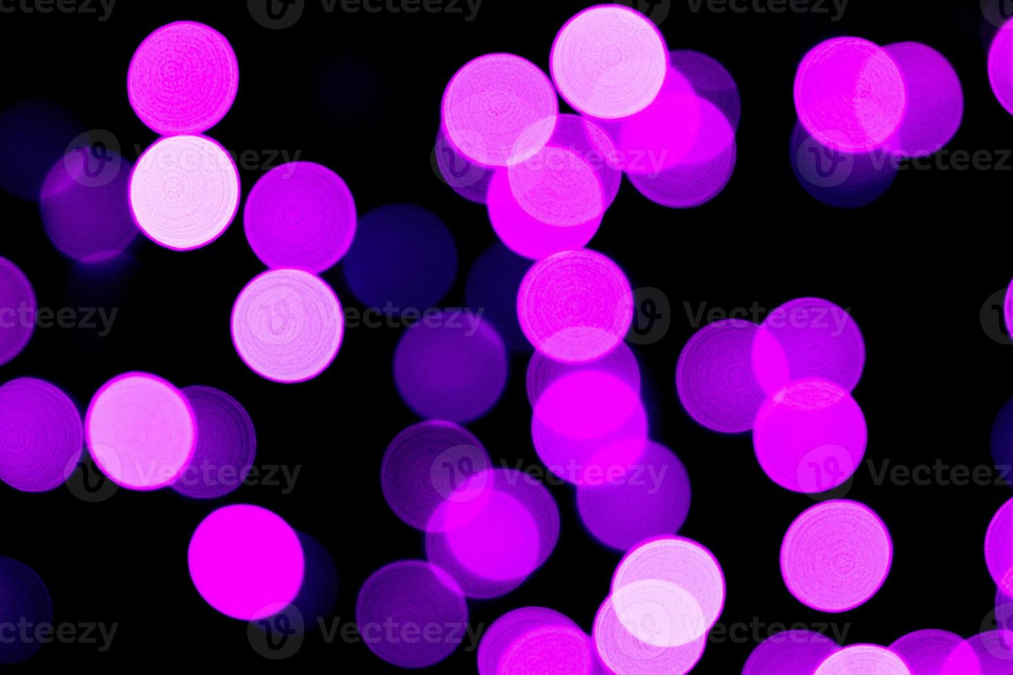 bokeh roxo abstrato sem foco em fundo preto. desfocado e desfocado muitas luzes redondas foto