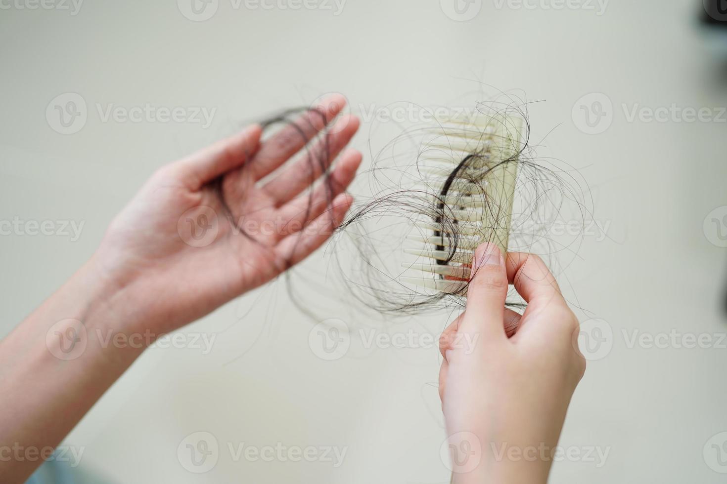 mulher asiática tem problema com perda de cabelo comprido anexar a escova de pente. foto