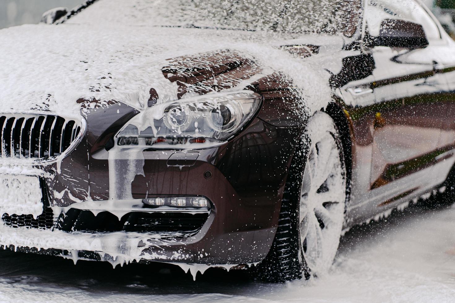 imagem de carro coberto de espuma, lavado por xampu automático no lava-jato. conceito de serviço de limpeza. espuma automática. lavagem de veículos foto