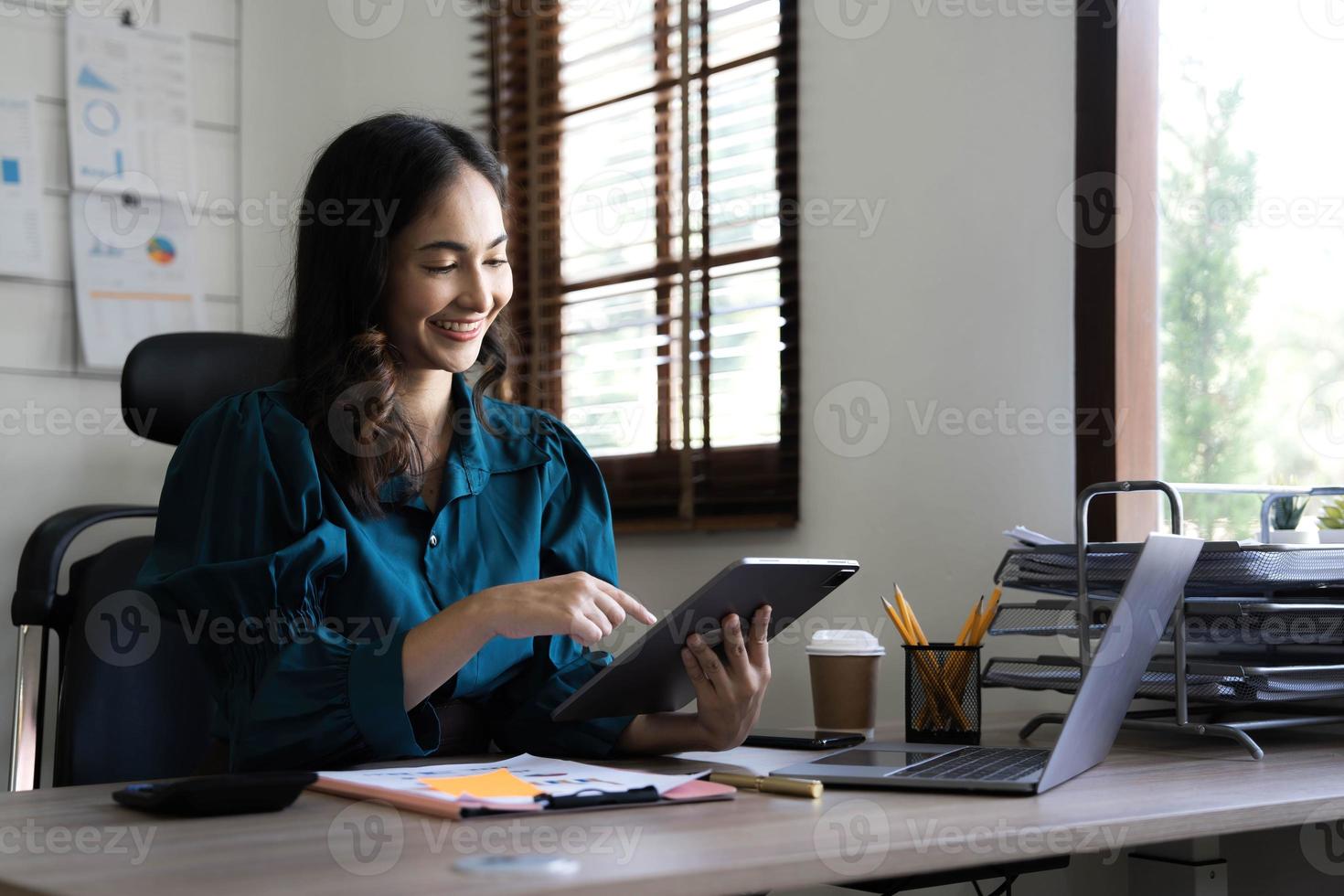 jovem empresária asiática trabalha em tablet com laptop no escritório. foto