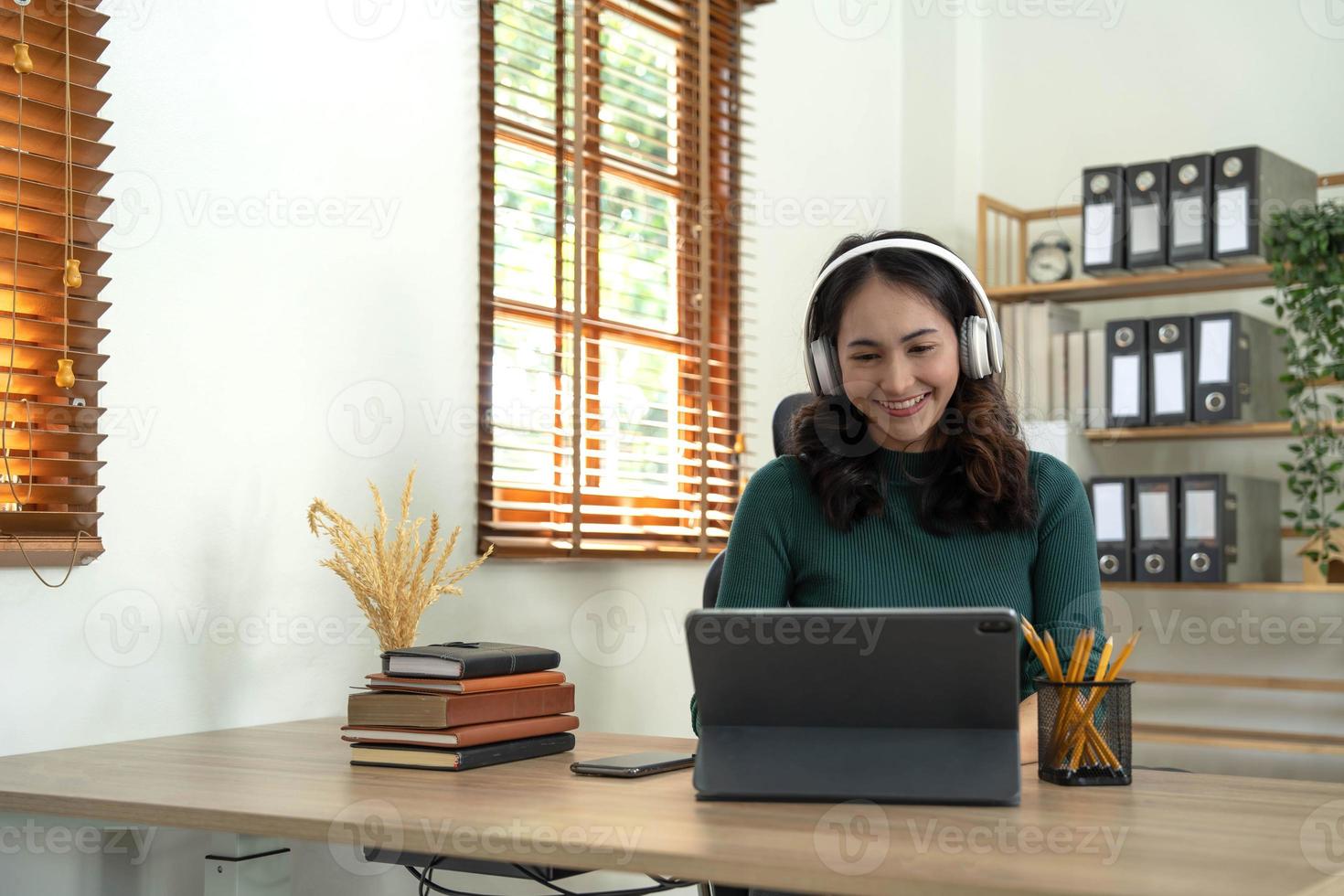 mulher sorridente usando fones de ouvido sem fio trabalhando digitando no notebook sente-se na mesa no local de trabalho do escritório. aproveite o processo de e-learning, uso fácil e confortável do aplicativo, ouça música durante o conceito de dia de trabalho foto