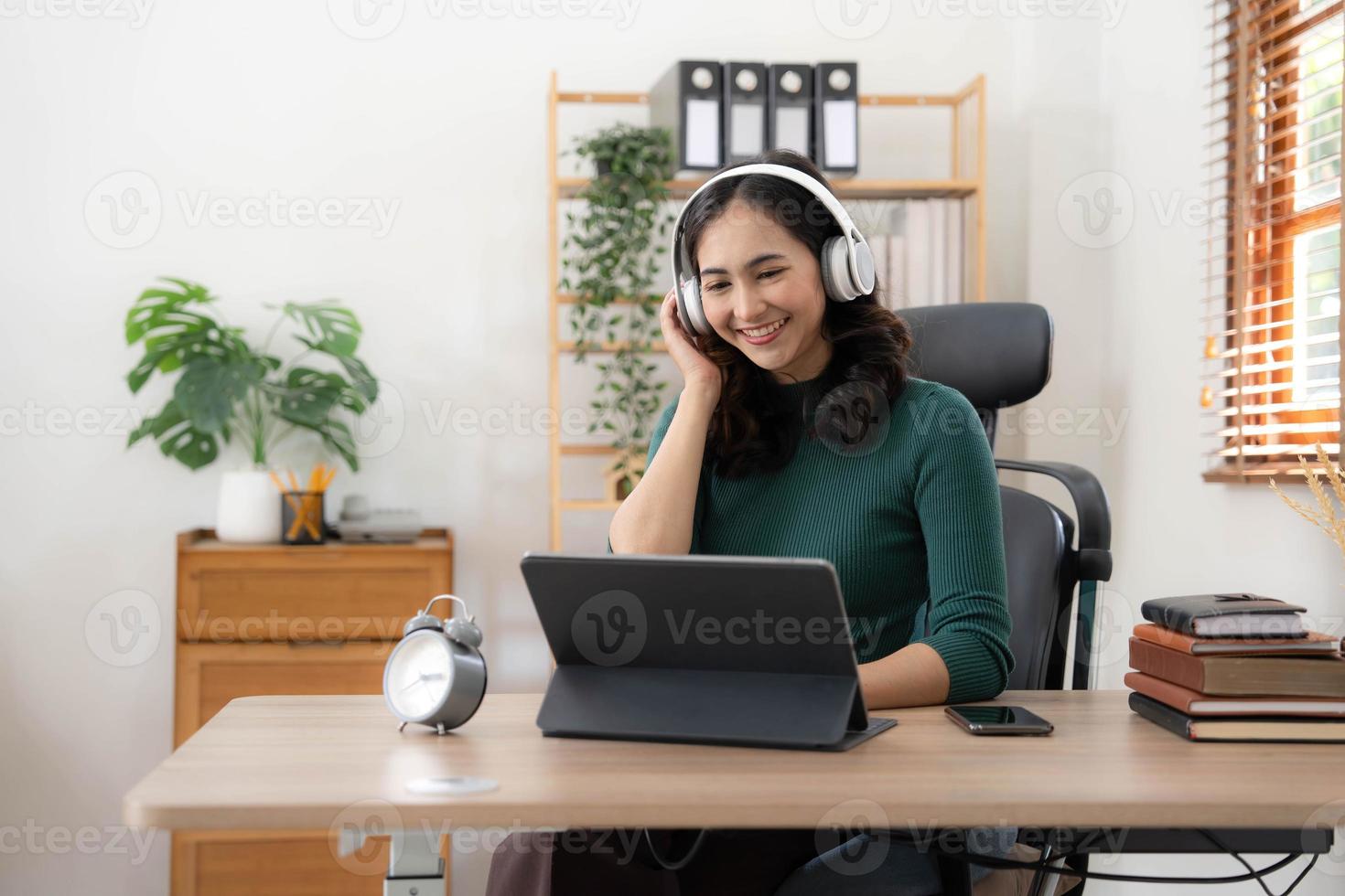 jovem mulher asiática usando fones de ouvido para estudar online com seu professor, a garota está feliz em aprender. foto